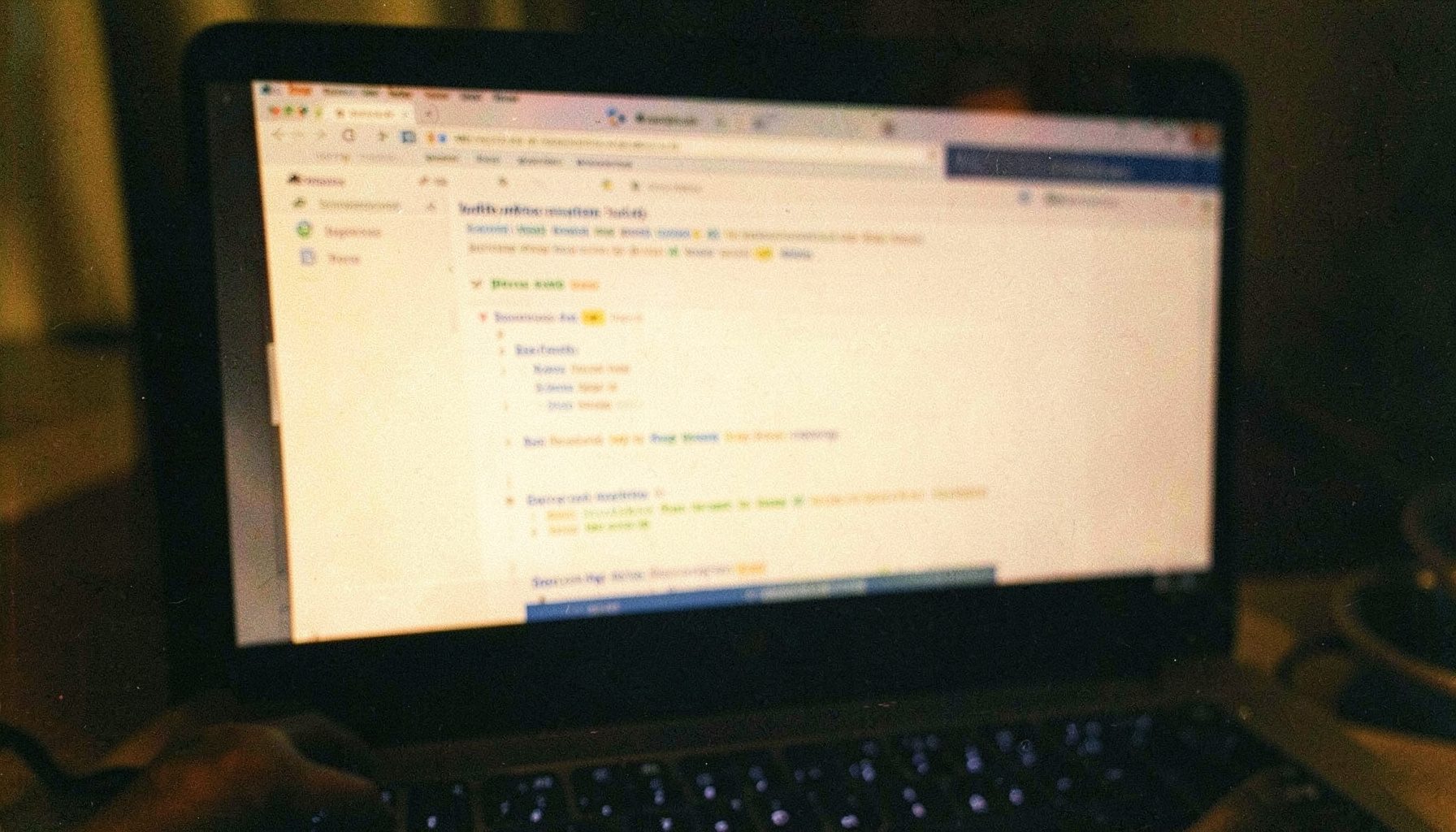 A close-up analog film photograph of a laptop screen displaying a search engine results page, warm amber and deep navy tones, shallow depth of field with visible grain.